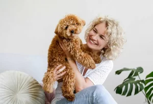 Woman is holding her poodle dog