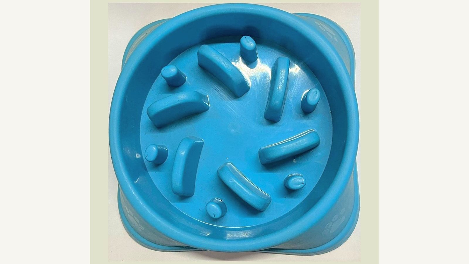 A blue plastic slow feeder dog bowl with raised ridges seen from above